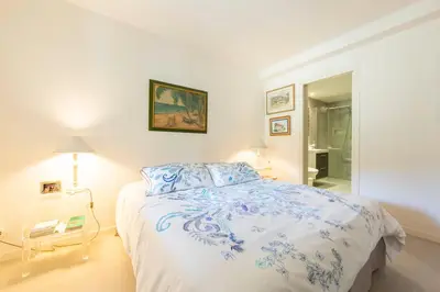 a white bedroom with a blue and white bed at Large Provencal villa with swimming pool in lush greenery LIVE IN CANNES in Vallauris