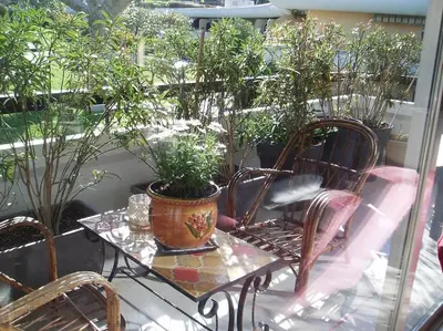 a table and chairs with plants on a balcony at 80m2 dans Parc Classé, Piscine, Calme, 5mn de Cannes in Le Cannet