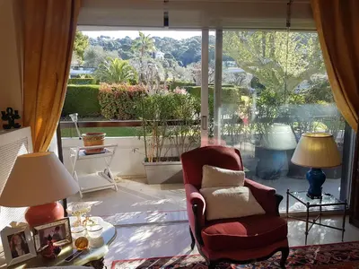 a living room with a chair and a large window at 80m2 dans Parc Classé, Piscine, Calme, 5mn de Cannes in Le Cannet