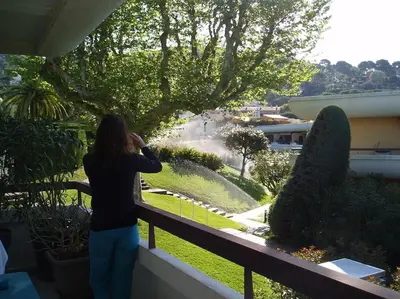 a woman standing on a balcony looking at a garden at 80m2 dans Parc Classé, Piscine, Calme, 5mn de Cannes in Le Cannet