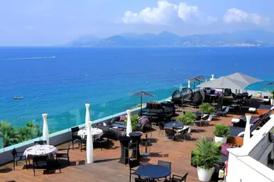 a balcony with tables and chairs and the ocean at HENRI CAMILLE REAL ESTATE - Rouaze - Studio 50m Croisette in Cannes