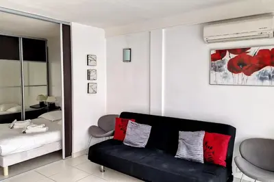 a living room with a black couch and a bed at HENRI CAMILLE REAL ESTATE - Rouaze - Studio 50m Croisette in Cannes