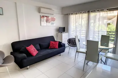 a living room with a black couch and a table at HENRI CAMILLE REAL ESTATE - Rouaze - Studio 50m Croisette in Cannes