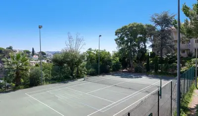 a tennis court with a net and trees at Profitez du Festival du Soleil de Cannes in Cannes