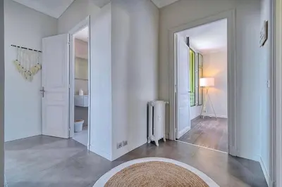 a living room with white walls and a large mirror at IMMOGROOM - Large Apartment - Parking - Air conditioning - Sea view - Wifi in Cannes