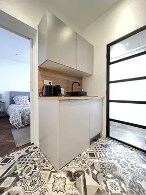 a kitchen with white cabinets and a door leading to a bedroom at LOENA CANNES CENTRE - 2 pièces rénové - 4 personnes - proche croisette palais festival plage - internet gratuit - climatisation - non fumeur in Cannes