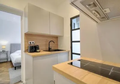 a kitchen with white cabinets and a bed in a room at LOENA CANNES CENTRE - 2 pièces rénové - 4 personnes - proche croisette palais festival plage - internet gratuit - climatisation - non fumeur in Cannes
