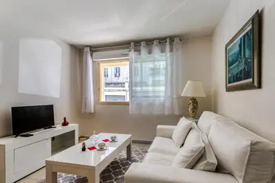 a living room with a white couch and a tv at Appartement Clap d'Or - Welkeys in Cannes