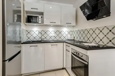 a kitchen with white cabinets and a microwave at Appartement Clap d'Or - Welkeys in Cannes