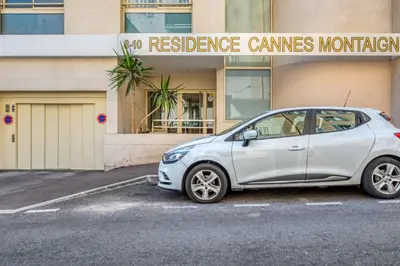 a white car parked in a parking lot in front of a building at Appartement Clap d'Or - Welkeys in Cannes