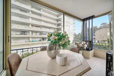 a vase of flowers on a table in a room with windows at IMMOGROOM - 2 BR - Air conditioning - Wifi - Terrace - Common parking in Cannes