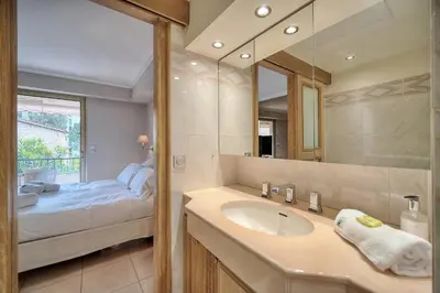 a bathroom with a sink and a bed and a mirror at IMMOGROOM - 2 BR - Air conditioning - Wifi - Terrace - Common parking in Cannes
