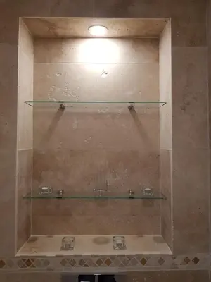 a shower with three glass shelves on the wall at Appartement en bord de mer in Cannes
