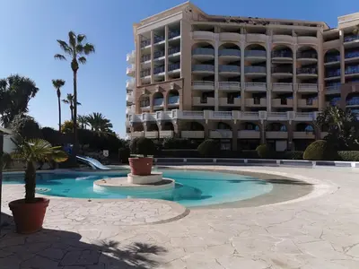 a swimming pool in front of a large building at Appartement en bord de mer in Cannes