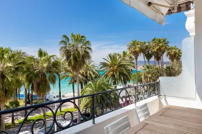 a balcony with a view of the beach and palm trees at CROISETTE - 2 Pièces rénové avec vue Mer in Cannes