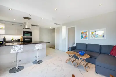 a living room with a blue couch and a kitchen at CROISETTE - 2 Pièces rénové avec vue Mer in Cannes