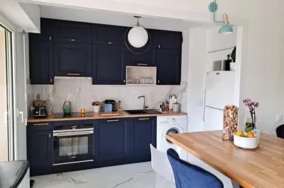 a kitchen with navy blue cabinets and a wooden table at HENRI CAMILLE RE - Passy 2 -Beautiful one bedroom swimming pool and parking in Cannes