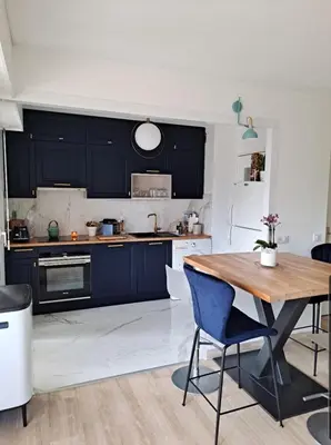 a kitchen with black cabinets and a wooden table at HENRI CAMILLE RE - Passy 2 -Beautiful one bedroom swimming pool and parking in Cannes