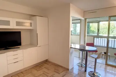 a living room with a television and a table and chairs at HENRI CAMILLE REAL ESTATE - Latour - Studio 150m Martinez in Cannes