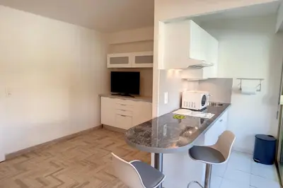 a kitchen with a counter and chairs in a room at HENRI CAMILLE REAL ESTATE - Latour - Studio 150m Martinez in Cannes