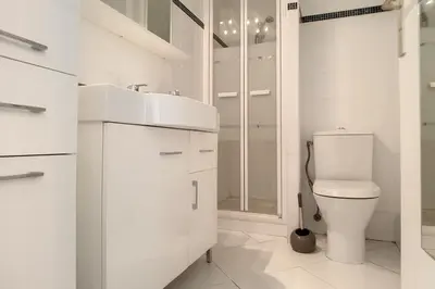 a white bathroom with a toilet and a sink at HENRI CAMILLE REAL ESTATE - Latour - Studio 150m Martinez in Cannes