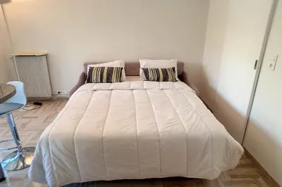 a bed in a bedroom with a white comforter and pillows at HENRI CAMILLE REAL ESTATE - Latour - Studio 150m Martinez in Cannes