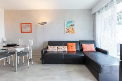a living room with a black couch and a table at Florida 35m studio with sea views close to the Croisette in Cannes