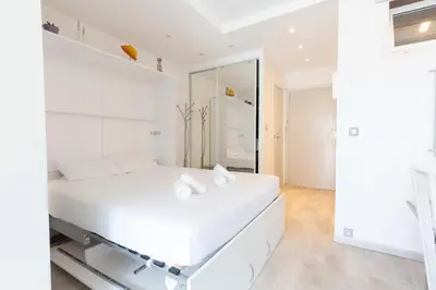 a white bedroom with a white bed and a mirror at Florida 35m studio with sea views close to the Croisette in Cannes