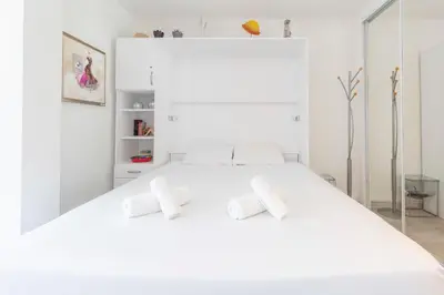 a white bedroom with a large white bed with two pillows at Florida 35m studio with sea views close to the Croisette in Cannes