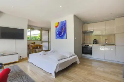 a bedroom with a white bed and a kitchen at Studio A/C La Californie with patio by Olidesi in Cannes