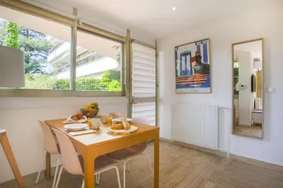 a dining room with a table and chairs and a window at Studio A/C La Californie with patio by Olidesi in Cannes