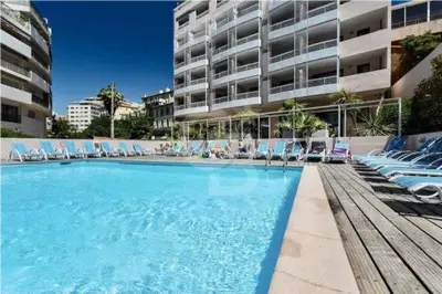 a large swimming pool with chairs and a building at Fantastic located studio in Cannes