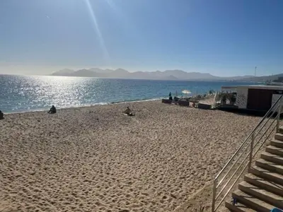 a beach with people sitting on the sand and the water at Fantastic located studio in Cannes