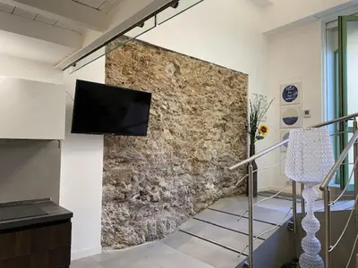 a living room with a stone wall with a flat screen tv at Sunflower apartments in Cannes