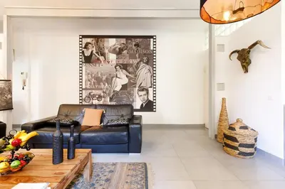 a living room with a black leather couch at Le Cocon des Artistes - Coeur de Cannes - Spacieux - Terrasse - Clim in Cannes