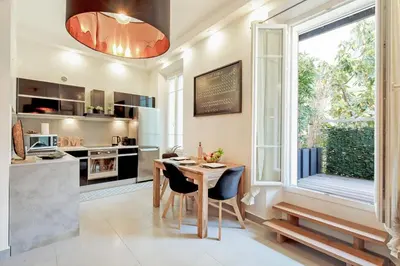 a kitchen and dining room with a table and a window at Le Cocon des Artistes - Coeur de Cannes - Spacieux - Terrasse - Clim in Cannes