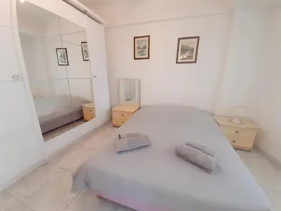 a white bedroom with a bed and a mirror at Palais des Iles in Cannes
