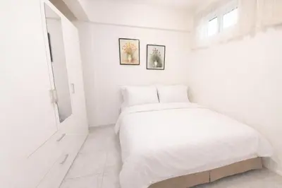 a white bedroom with a bed and a window at Palais des Iles in Cannes