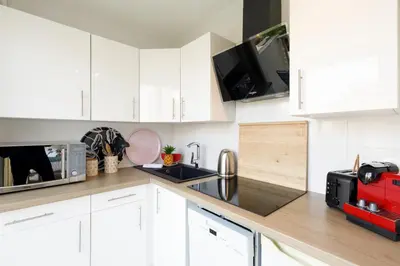 a kitchen with white cabinets and a red appliance at Bleu Croisette YourHostHelper in Cannes