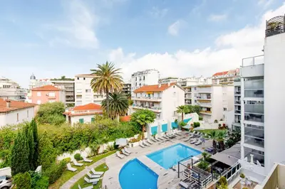 an apartment with a swimming pool and buildings at Bleu Croisette YourHostHelper in Cannes