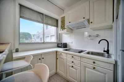a kitchen with white cabinets and a sink and a window at IMMOGROOM - Cosy - California - Close to everything in Cannes