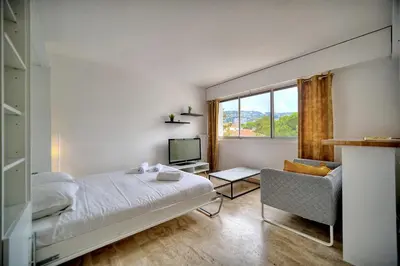a bedroom with a bed and a chair and a television at IMMOGROOM - Cosy - California - Close to everything in Cannes