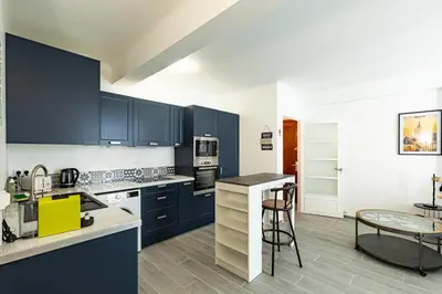a kitchen with blue cabinets and a table and chairs at IMMOGROOM - Renovated - Terrace - Air conditioning - Quiet - Carnot in Cannes