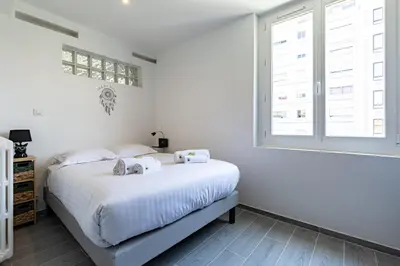 a white bedroom with a bed and a window at IMMOGROOM - Renovated - Terrace - Air conditioning - Quiet - Carnot in Cannes