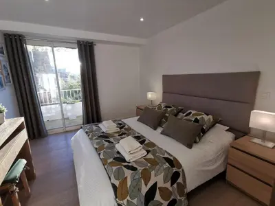 a bedroom with a large bed and a large window at CHESTER Riviera Escape - Appartement calme, terrasse & clim proche Croisette et centre in Cannes