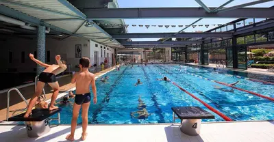 two children are standing in a swimming pool at CHESTER Riviera Escape - Appartement calme, terrasse & clim proche Croisette et centre in Cannes