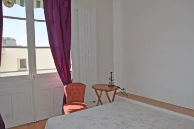 a bedroom with a bed and a chair and a window at Palais Alexandre III in Cannes