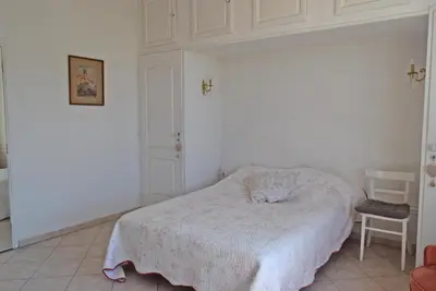 a white bedroom with a bed and a chair at Palais Alexandre III in Cannes