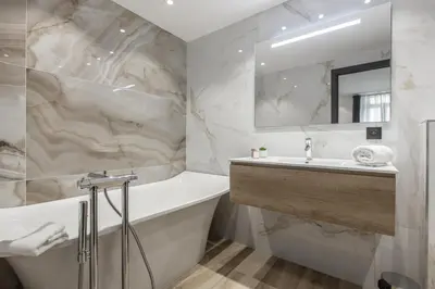 a white bathroom with a tub and a sink at Résidence Topaze - Central - Luxurious - 50m Croisette Palais - LRA CANNES in Cannes