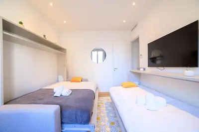 a bedroom with two beds and a flat screen tv at L'Elégance Hoche - Congrès Palais - Plage Croisette - Cannes Centre - Clim in Cannes